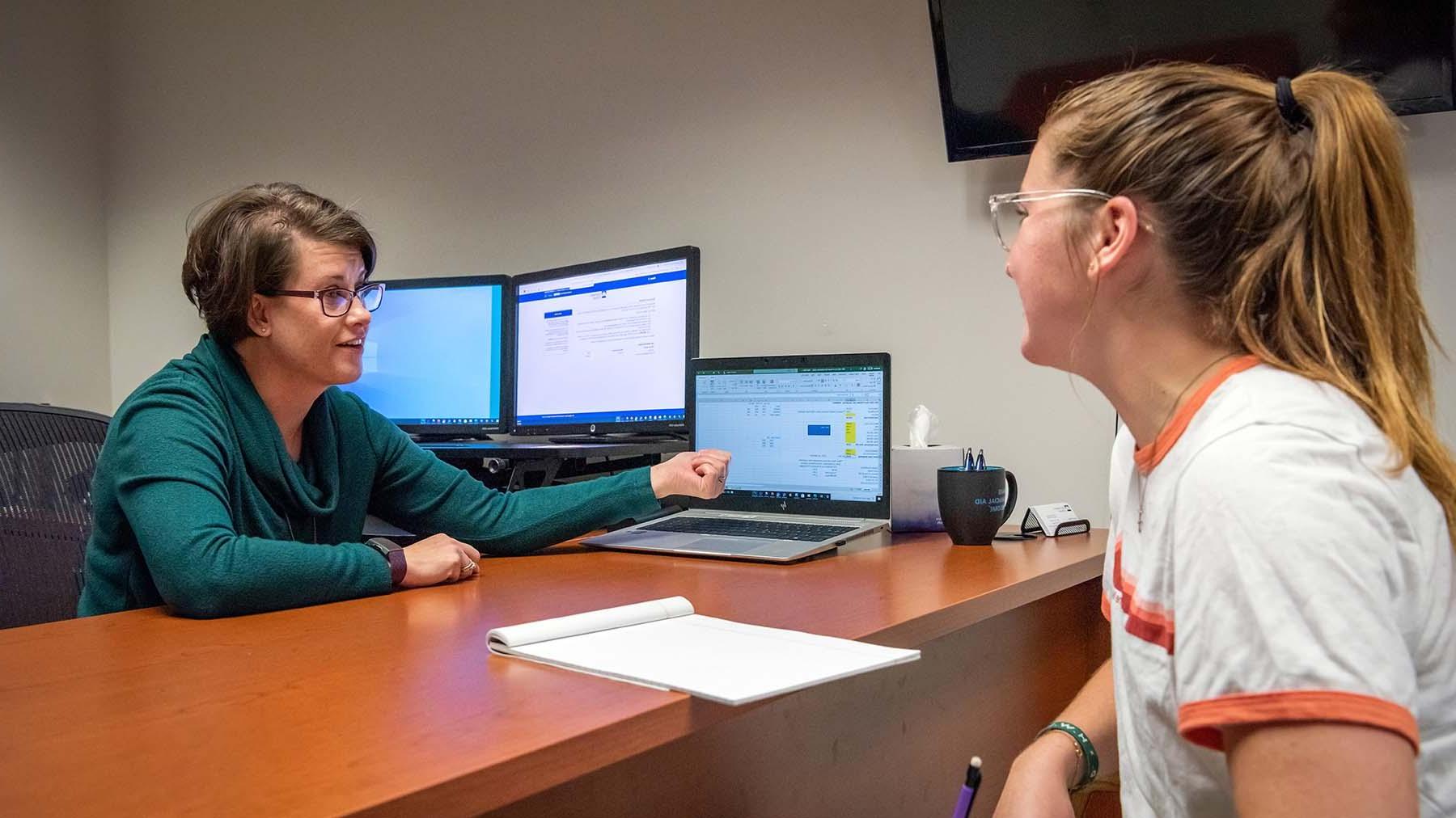 Financial aid representative meeting with student in her office.